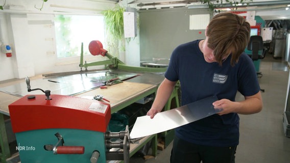 Ein junger Mann arbeitet an einer Maschine in einer Werkstatt. © Screenshot 