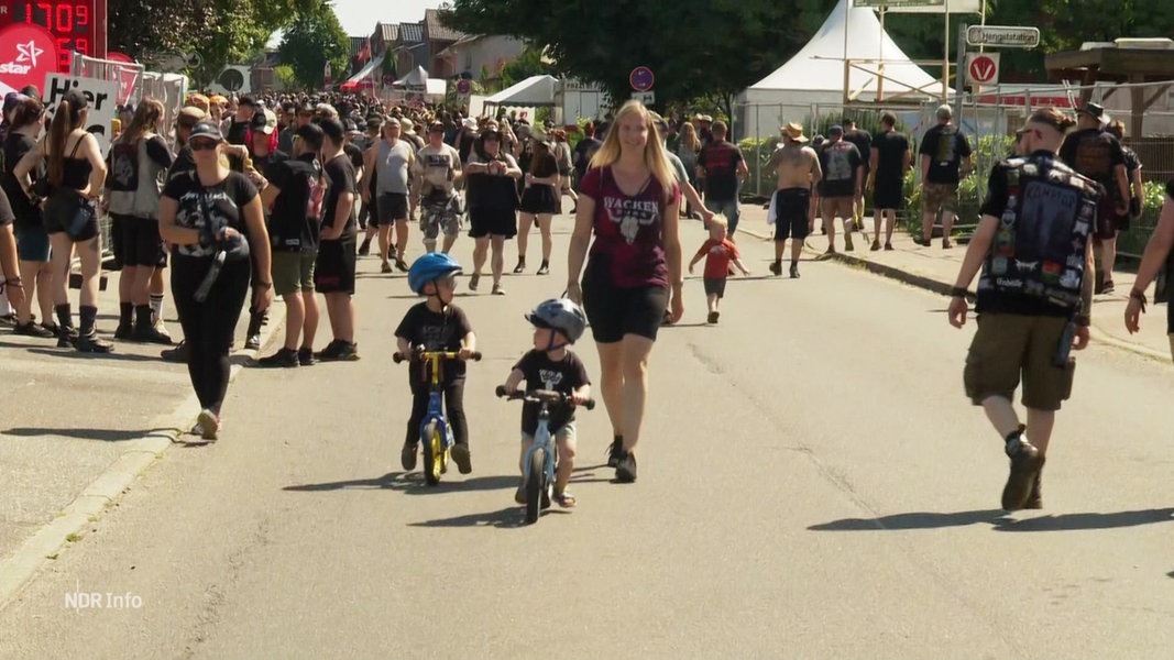 Zwei Kinder fahren auf Laufrädern über das Festivalgelände in Wacken.