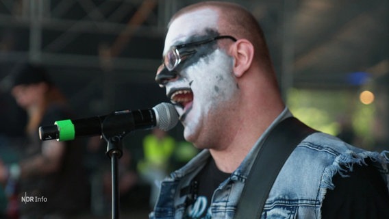 Ein Mitglied der inklusiven Band "Amalgam" beim Auftritt beim Wacken-Festival am Mikrofon. © Screenshot 