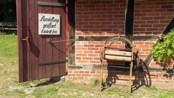 An der Tür einer alten Fachwertkscheune hängt ein Schild mit der Aufschrift "Ausstellung geöffnet, Eintritt frei". © Screenshot 