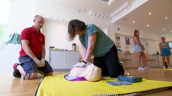 Ein Frau übt an einer Puppe eine Herzdruckmassage. © Screenshot 