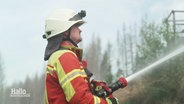 Ein Feuerwehrmann steht im Harzer Wald und richtet einen Wasserstrahl auf sein Ziel. © Screenshot 