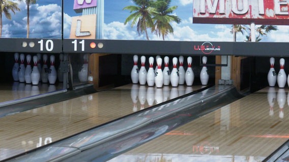 Kegel stehen aufgereiht auf einer Bowlingbahn. © Screenshot 