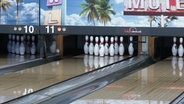 Kegel stehen aufgereiht auf einer Bowlingbahn. © Screenshot 