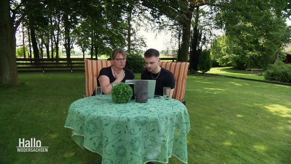 Eine Mutter und ihr Sohn sitzen in einem Garten und suchen im Internet nach Lebenszeichen ihres vermissten Sohnes, beziehungsweise Bruders. © Screenshot 