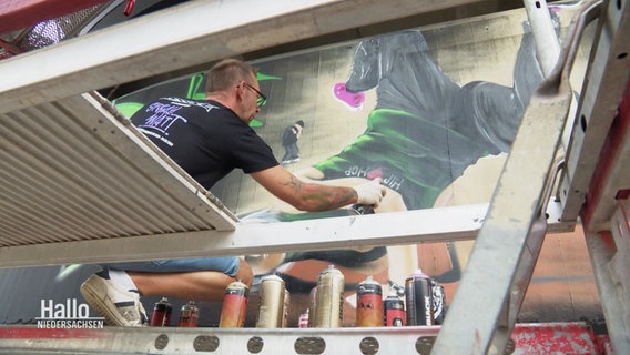 Ein Sprayer verschönert im Rahmen des Street-Art Festivals die Fassade eines Parkhauses. © Screenshot 