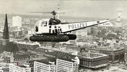 Schwarz, weiße Aufnahme von dem Polizeihubschrauber "Libelle" wie er über Hamburg fliegt. © Screenshot 