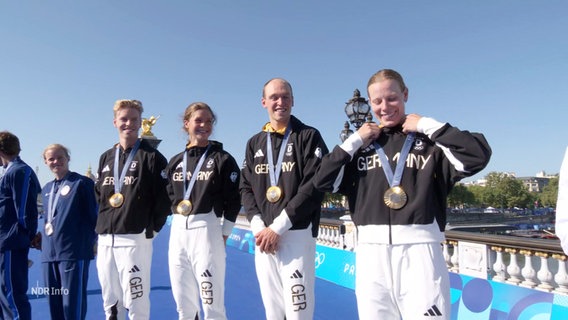 Das deutsche Triathlon-Staffel-Team um Lasse Lührs bei der Siegerehrung nach ihrem ersten Platz bei den Olympischen Spielen in Paris. © Screenshot 