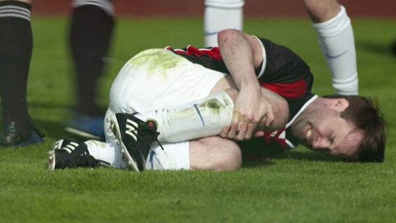 Ein Fußballspieler liegt verletzt auf dem Boden und hält sich ein Knie. © Screenshot 