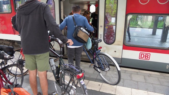 Mehrere Reisende mit Fahrrädern warten beim Einsteigen vor der Tür eines Regionalzuges. © Screenshot 