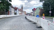 Sperrzäune stehen auf dem Kopfsteinpflaster der Zufahrtsstraße. © Screenshot 