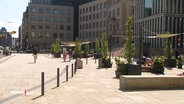 Menschen sitzen auf Sitzmöbeln in der Hamburger Innenstadt. © Screenshot 