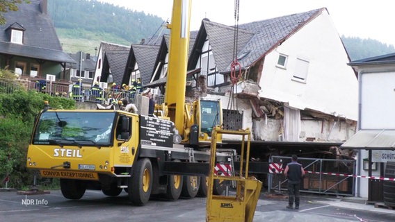 Ein Kranwagen vor einem eingestürzten Haus. © Screenshot 