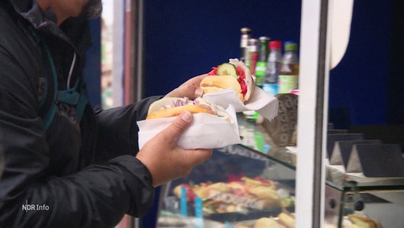 Eine Person kauft Fischbrötchen an einem Stand am Rostocker Hafen. © Screenshot 