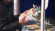 Eine Person kauft Fischbrötchen an einem Stand am Rostocker Hafen. © Screenshot 