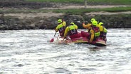 Ein Schlauchboot in dem Rettungskräfte sitzen und paddeln. © Screenshot 