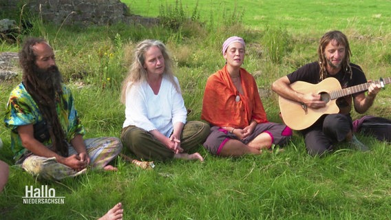 Teinehmer:innen des Rainbow-Family-Camps meditieren und singen. © Screenshot 