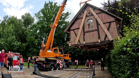 Ein Reetdachhaus wird auf einen Schwerlasttransport geladen. © Screenshot 