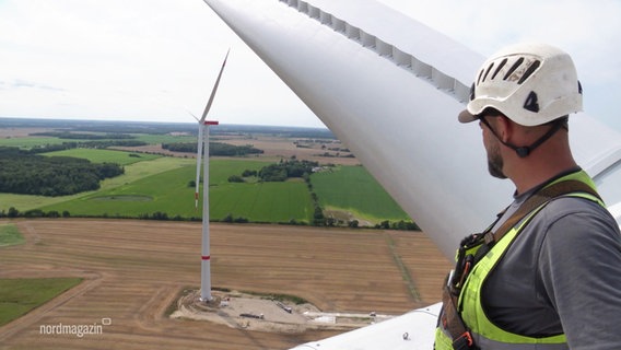 Ein Ingeneur steht auf einer Windkraftanlgae. © Screenshot 