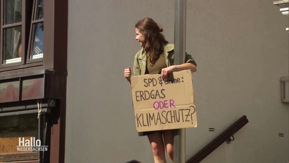 Luisa Neubauer ist mit einem Protestschild auf eine Laterne geklettert. © Screenshot 