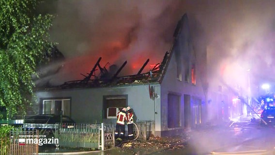 Feuerwehrleute stehen vor einem brennenden Haus. © Screenshot 