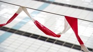 Ein Absperrband hängt in einer Schwimmhalle. © Screenshot 