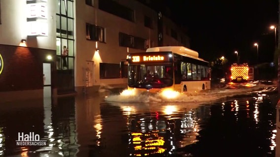 Ein Bus fährt durch eine überschwemmte Straße. © Screenshot 