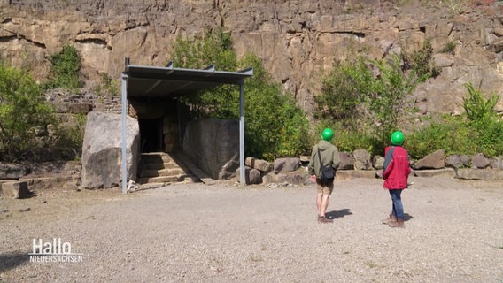 Zwei Personen vor dem Eingang zur Schillat-Höhle. © Screenshot 