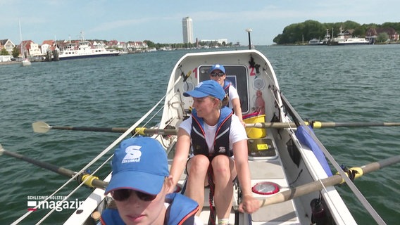 Drei Frauen sitzen in einem Spezialruderboot. © Screenshot 