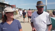 Zwei Personen auf einer Strandpromenade. © Screenshot 