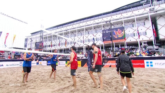 Das deutsche Team Nils Ehlers und Clemens Wickler tragen rote Trikots und klatschen sich mit dem niederländischen Team im blauen Trikot nach dem Match bei der Beachvolleyball-EM 2024 ab. © Screenshot 