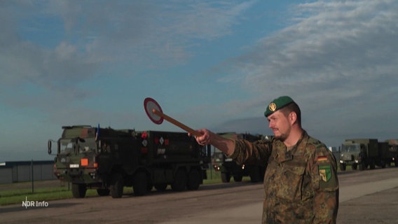 Ein Soldat zeigt Militär-LKW den Weg.. © Screenshot 