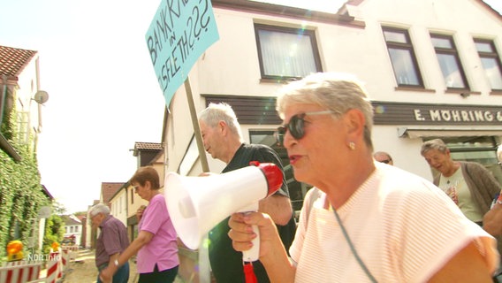 Eine Oma mit Megafon und Sonnenbrille auf einer Rentnerdemo. © Screenshot 