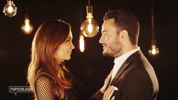 Jana Ina und ihr Mann Giovanni Zarrella in einem Musikvideo. Beide schauen sich verträumt in einer romantischen Atmosphäre in die Augen. © Screenshot 