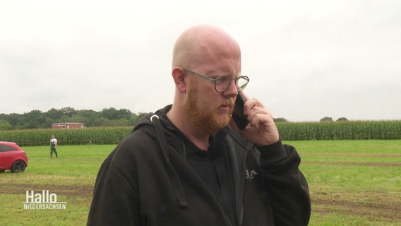 Carsten Thöles telefaniert auf einem Feld. Er hat eine Glatze und trägt Brille. © Screenshot 