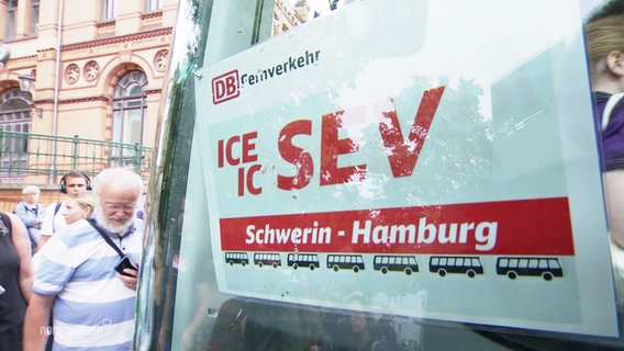 An einem Bus hängt ein Ersatzverkehr-Schild für die Strecke Schwerin Hamburg. © Screenshot 