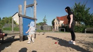 Eine junge Mutter mit ihrem Kind auf einem Spielplatz. © Screenshot 