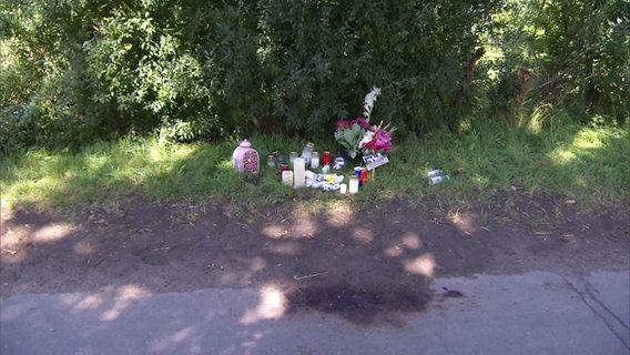 Blumen und Kerzen stehen am Straßenrand an der Unglücksstelle. © Screenshot 