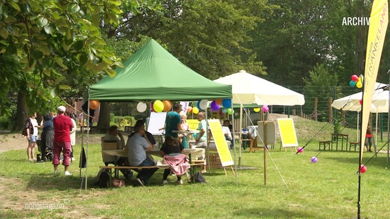 Auf einer Wiese wird ein Fest gefeiert, mit Zelten und Ballons. © Screenshot 