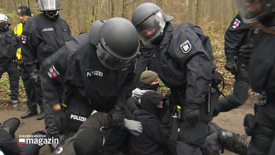 Polizei-Einsatzkräfte üben das Auseinanderbrechen einer Sitzblockade von Demonstranten. © Screenshot 