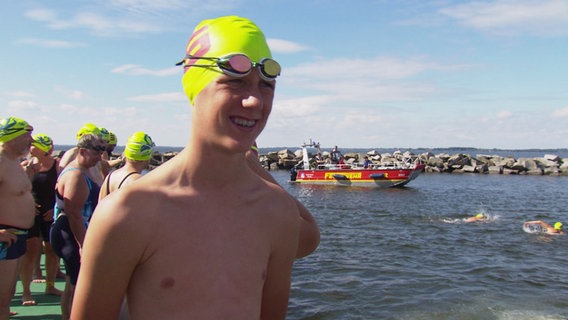 Julius Michel mit Schwimmbrille und neongelber Badekappe vor dem Start. © Screenshot 