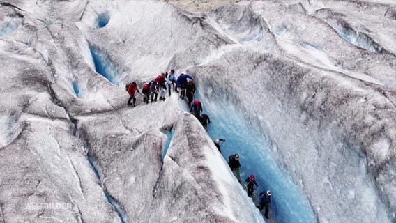 Mehrere Menschen klettern auf einem Gletscher. © Screenshot 