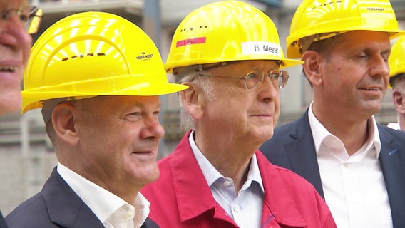 Bundeskanzler Olaf Scholz mit Vetretern der Meyer-Werft. Alle tragen gelbe Bauhelme. © Screenshot 