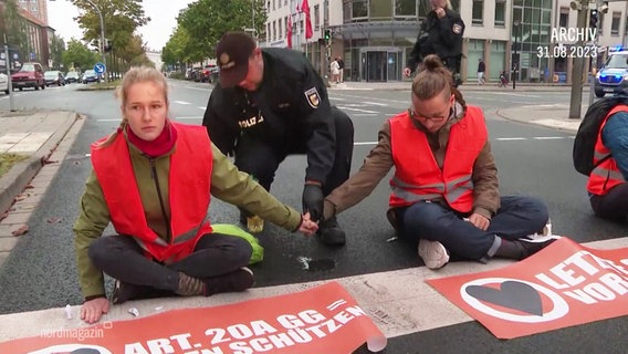 Sitzblockade der Letzten Generation auf einer Straße in Rostock. © Screenshot 