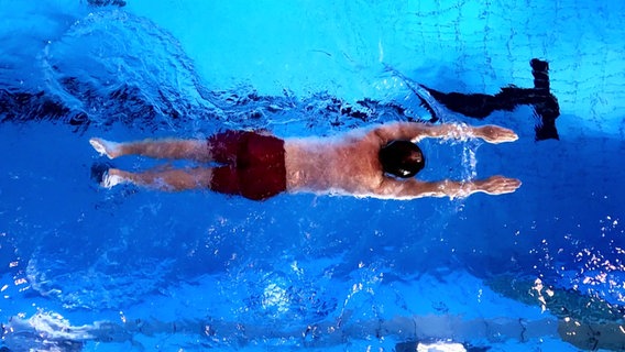 Ein Mann schwimmt. Aufgenommen von oben. © Screenshot 