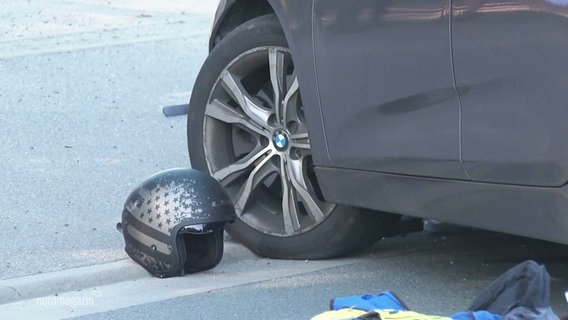 Ein Motorradhelm liegt auf der Straße neben den Reifen eines stehenden Pkws. © Screenshot 