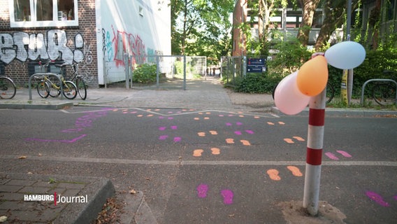 An einem Poller vor einer Schule sind Luftballons befestigt. © Screenshot 