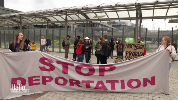 Demonstrierende am Flughafen halten ein Transparent mit der Aufschrift "Stop Deportation". © Screenshot 