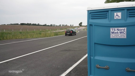 Eine Dixie-Toilette steht am Fahrbahnrand. © Screenshot 