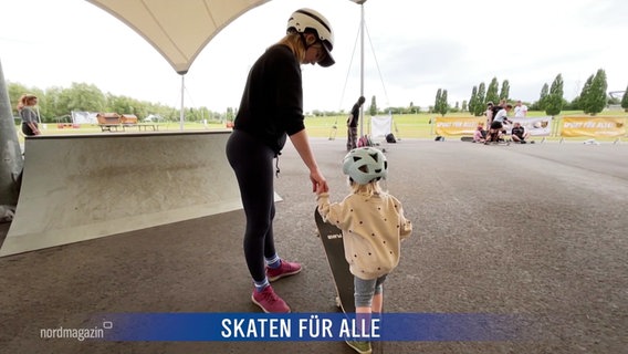 Ein Frau hält ein sehr junges Kind an der Hand, das versucht Skateboard zu fahren. © Screenshot 